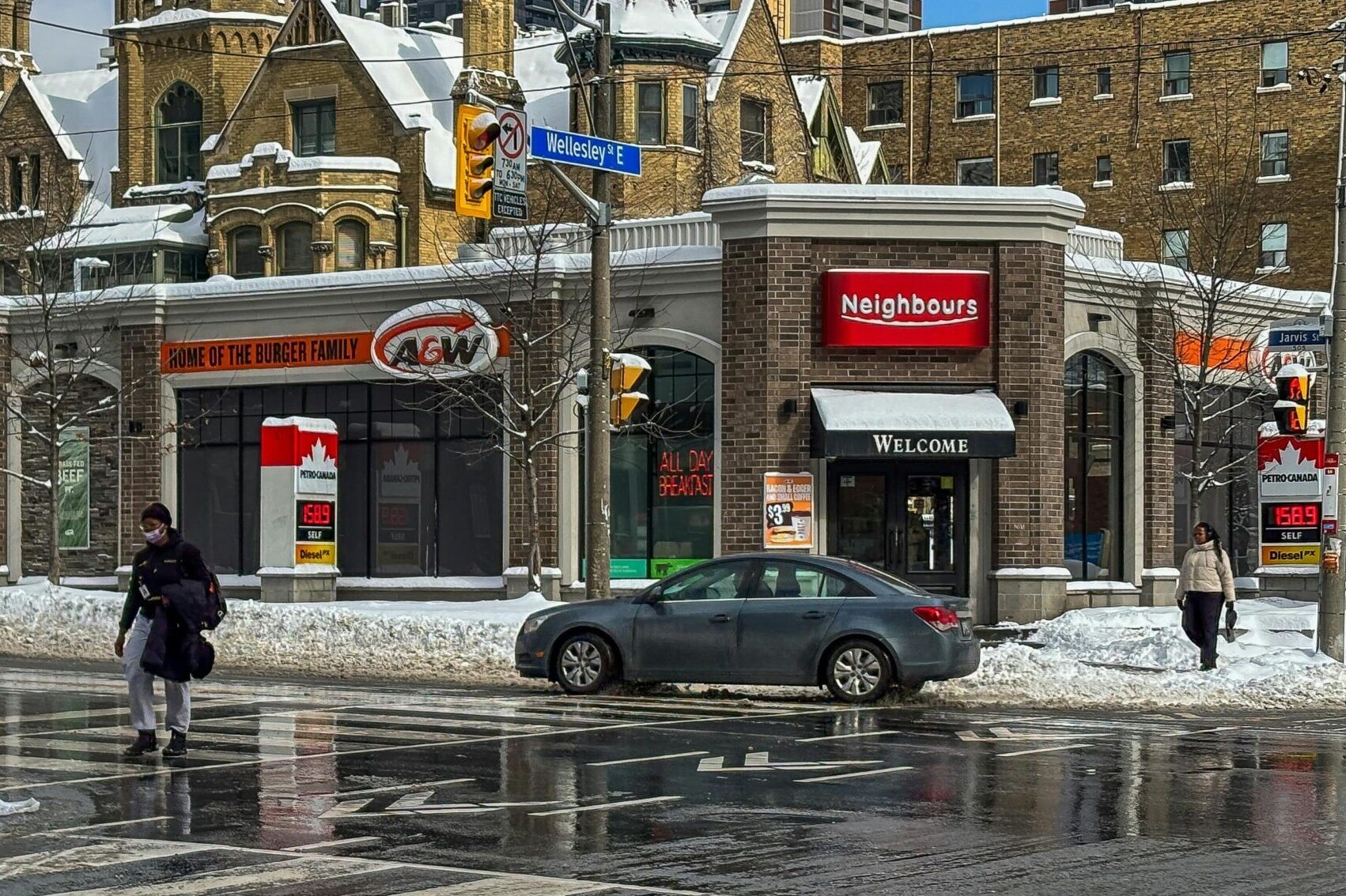 Busy intersection in downtown Toronto with street signs and a gas station