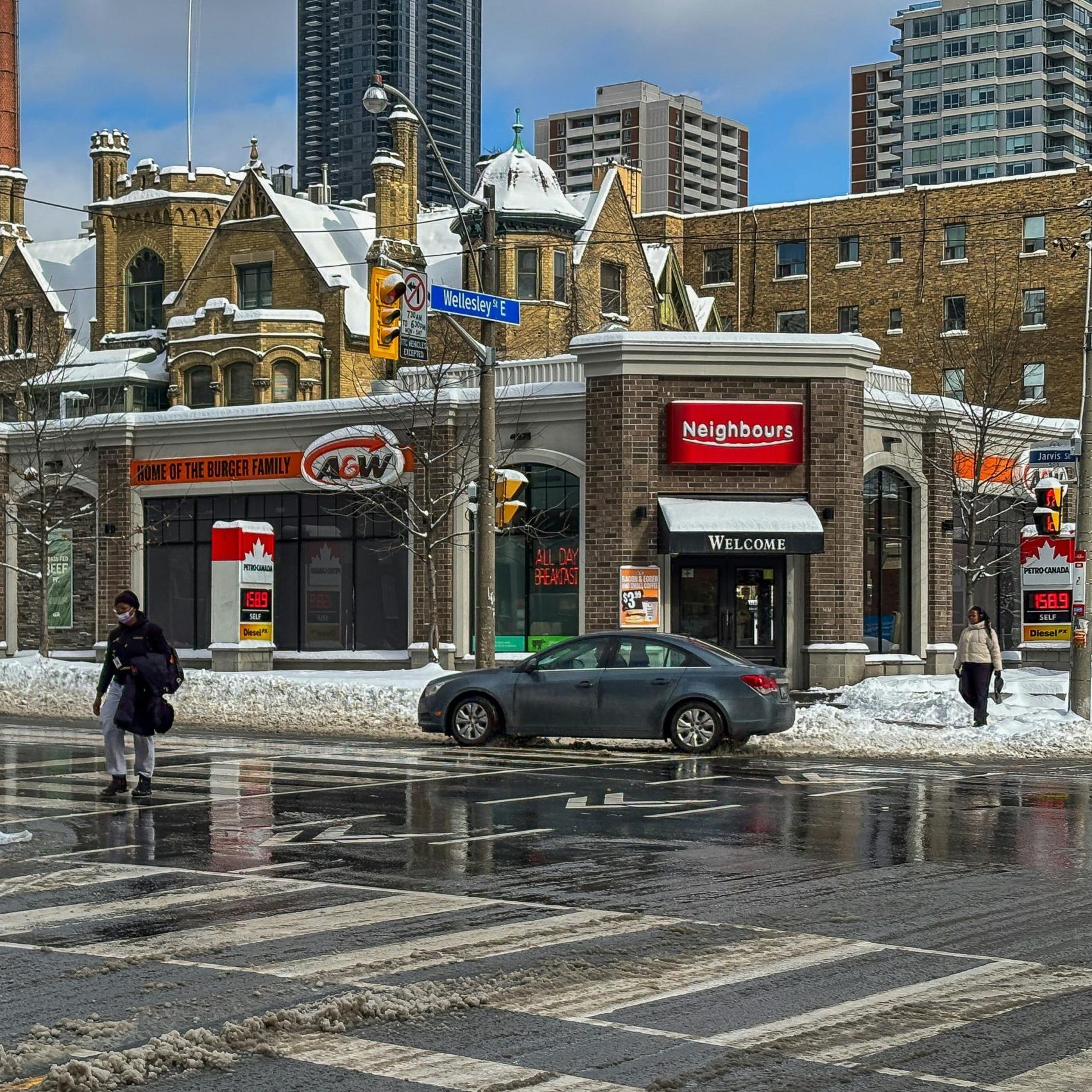 Busy intersection in downtown Toronto with street signs and a gas station