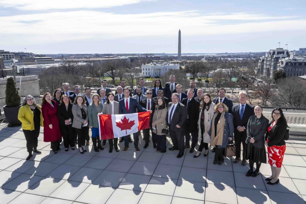 Members of the Canadian Chamber of Commerce attend an event in Washington DC and pose in front of the Capitol building with a Canadian flag
