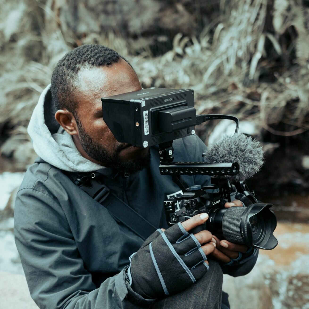 Man behind a film camera shooting outside near a river