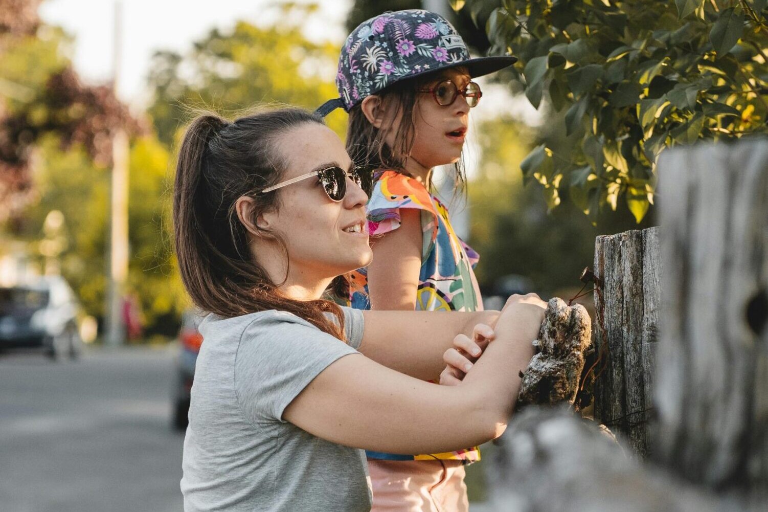 Small child and parent peek over a grey fence
