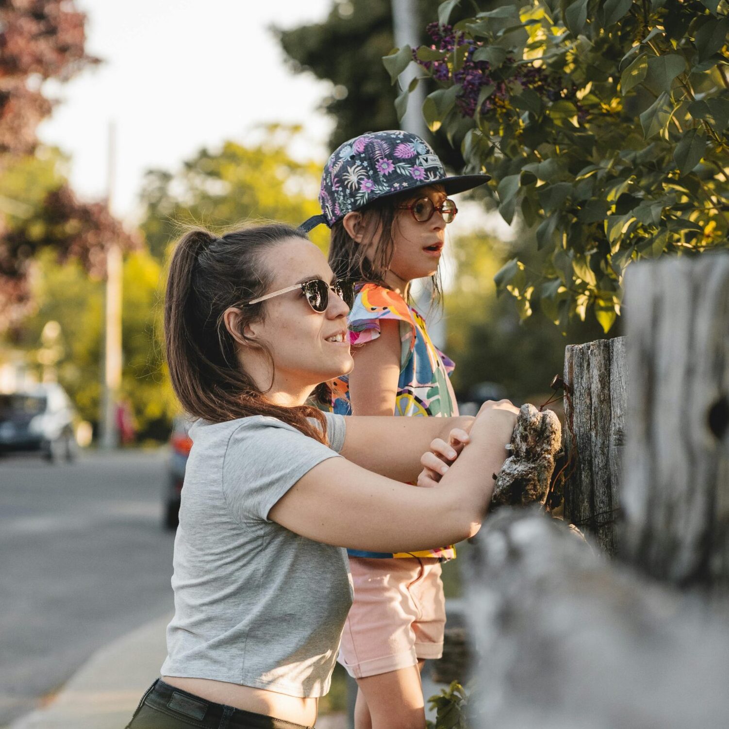 Small child and parent peek over a grey fence